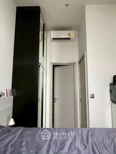 Modern bedroom with sleek black wardrobe and air conditioning unit.