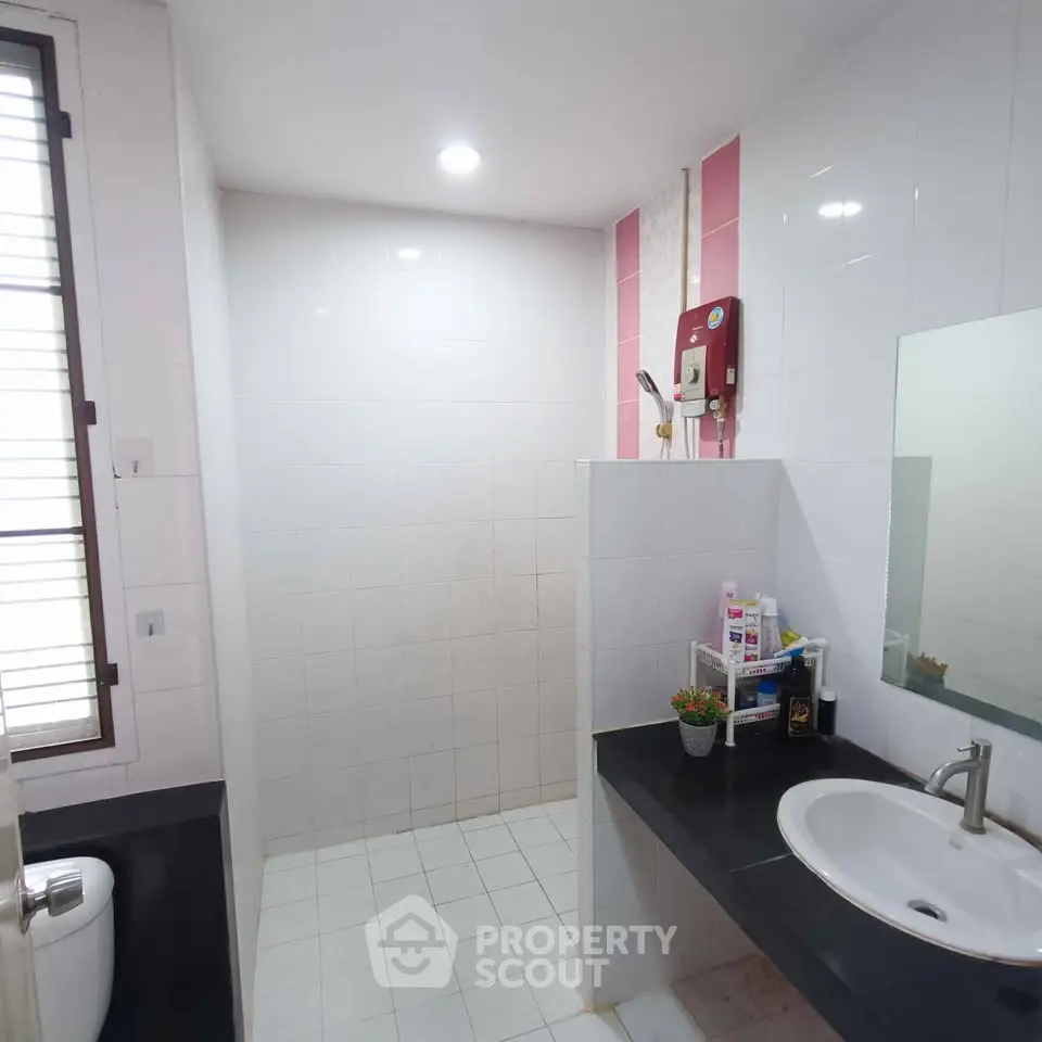 Modern bathroom with sleek fixtures and ample natural light, featuring a spacious shower area and stylish sink.