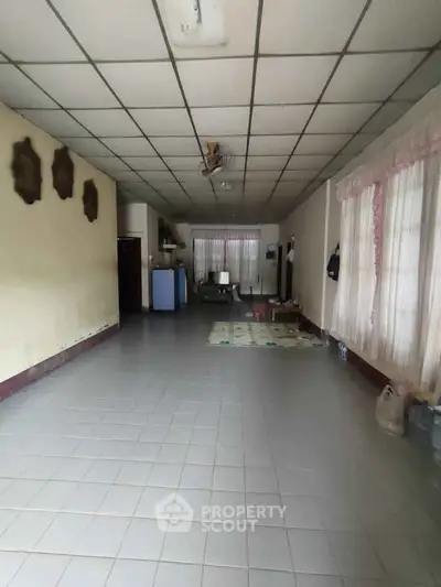 Spacious living room with tiled floor and large windows, ideal for family gatherings.
