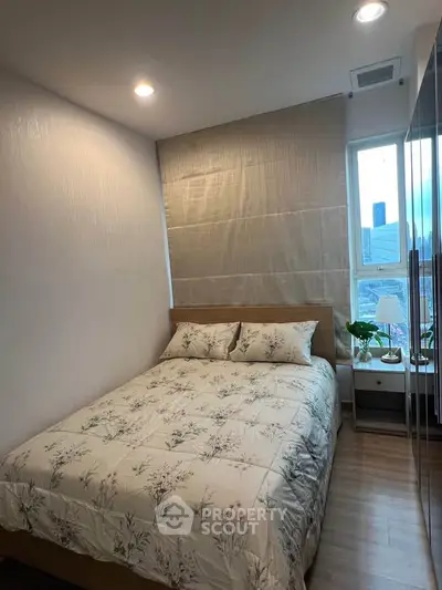 Cozy bedroom with floral bedding and natural light, perfect for relaxation and comfort.