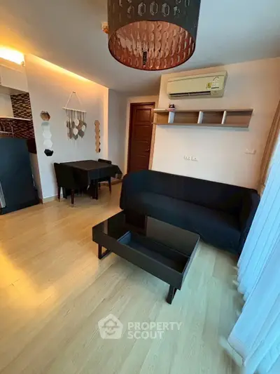 Modern living room with sleek black furniture and wooden flooring, featuring a cozy ambiance.
