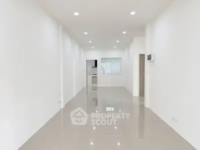 Spacious open-plan living area with sleek tiled flooring and modern kitchen view.