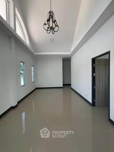 Spacious empty room with high ceiling and elegant chandelier in modern home.