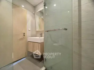 Modern bathroom with glass shower and sleek vanity in stylish apartment.