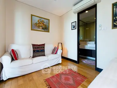 Charming living room with cozy sofa and stylish decor, featuring wooden flooring and modern air conditioning.