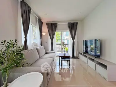 Modern living room with large windows, gray sofa, and sleek TV setup