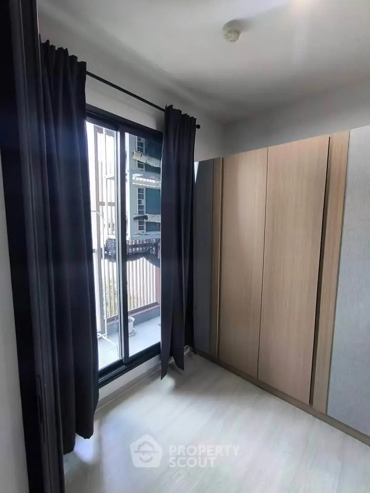 Modern bedroom with large window and sleek wardrobe, offering natural light and stylish storage solutions.