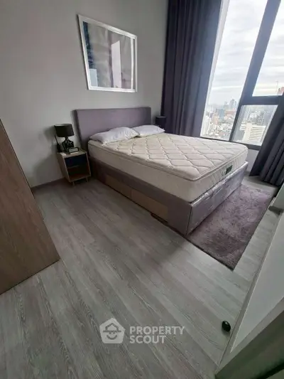 Modern bedroom with city view, featuring a stylish bed and sleek flooring, perfect for urban living.