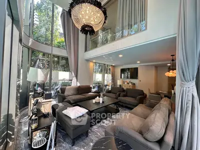 Luxurious double-height living room with elegant chandelier and modern furnishings.