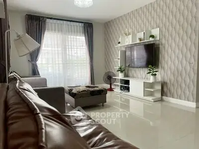 Modern living room with stylish decor, large TV, and natural light through elegant curtains.