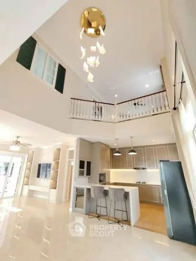 Luxurious open-plan kitchen with high ceilings and modern lighting in a spacious home.