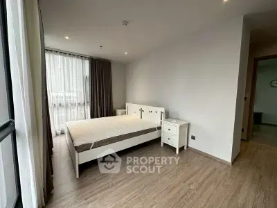 Spacious modern bedroom with large window and minimalist furniture in a stylish apartment.