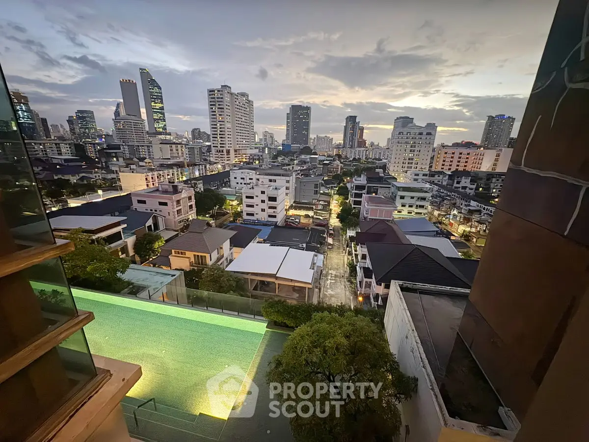 Stunning cityscape view from high-rise building with illuminated pool at dusk, showcasing urban living.
