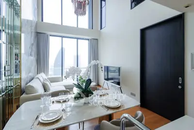 Luxurious modern living room with high ceilings and large windows offering stunning city views.