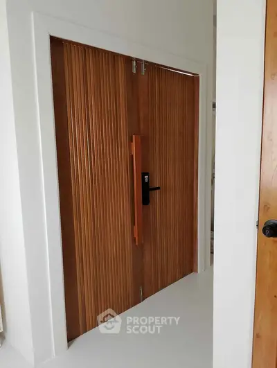 Elegant wooden double doors with modern handle in a minimalist interior.