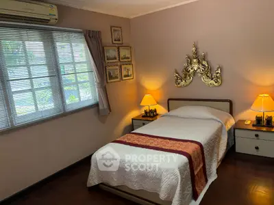 Cozy bedroom with elegant decor and warm lighting, featuring a single bed and vintage wall art.