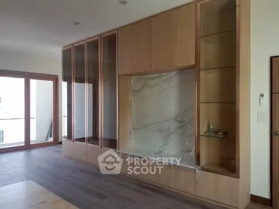 Spacious modern living room with elegant built-in wooden cabinetry and large windows for natural light.