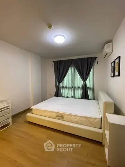 Spacious bedroom with modern decor and large window for natural light.