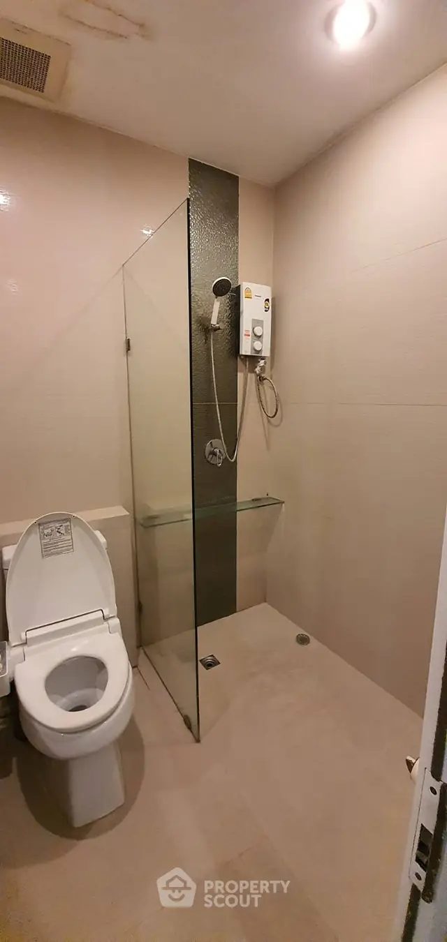 Modern bathroom with glass shower and toilet in minimalist design.