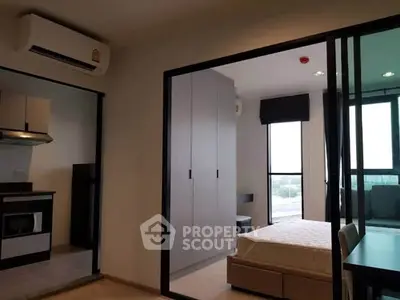 Modern apartment interior with bedroom and kitchen, featuring sleek design and ample natural light.