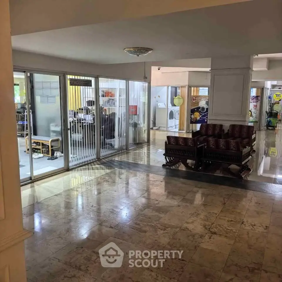 Spacious building lobby with marble flooring and glass-walled office area, ideal for commercial use.