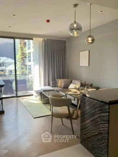 Modern living room with open kitchen and large windows offering natural light and balcony access.