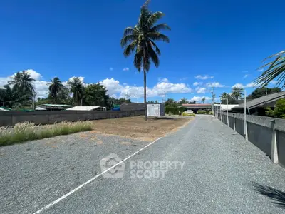 Spacious land plot with palm trees and clear blue sky, ideal for development.