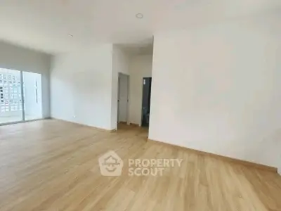 Spacious empty room with wooden flooring and natural light, ideal for customization.