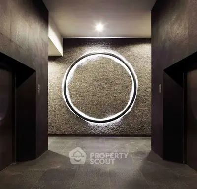 Modern building entrance with artistic circular wall feature and sleek design.