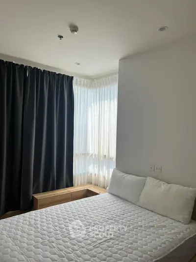 Cozy bedroom with natural light and modern decor, featuring a comfortable bed and stylish curtains.