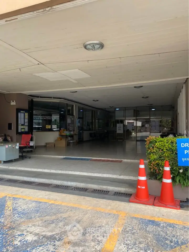Spacious building entrance with parking area and safety cones, ideal for commercial use.