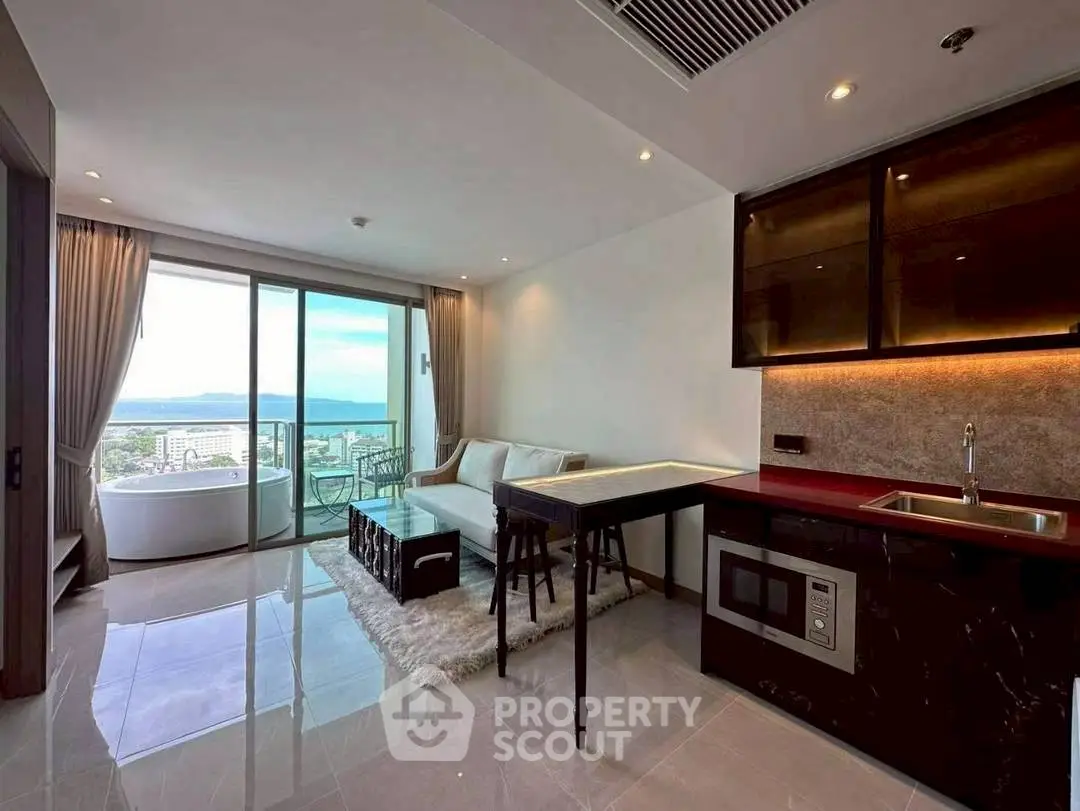 Modern open-plan living room with kitchen and stunning sea view balcony in luxury apartment.