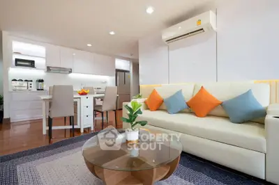 Modern living room with open kitchen, stylish decor, and cozy seating area.