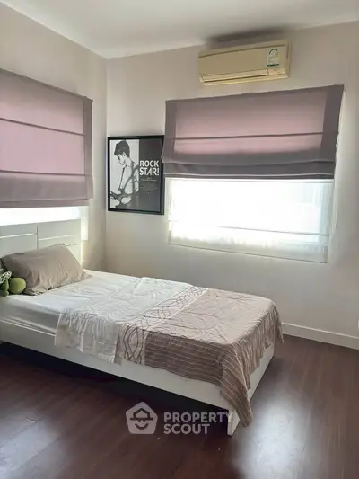 Cozy bedroom with modern decor and air conditioning, featuring stylish window treatments and hardwood flooring.