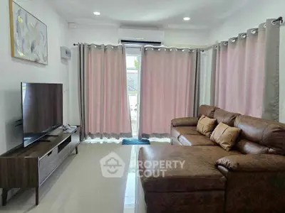 Cozy living room with modern brown leather sofa and large TV, perfect for relaxation.