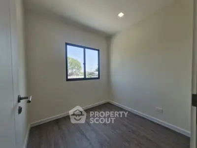 Bright empty room with large window and wooden flooring