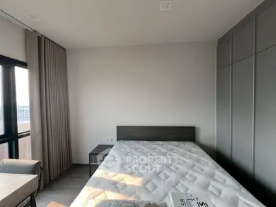 Modern bedroom with large window and sleek wardrobe in a contemporary apartment.