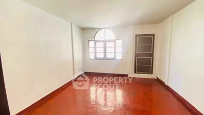 Spacious room with wooden flooring and large window, perfect for customization.