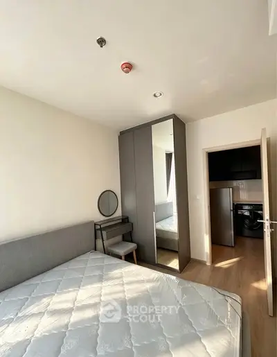 Modern bedroom with sleek wardrobe and natural light, featuring a cozy bed and stylish vanity area.