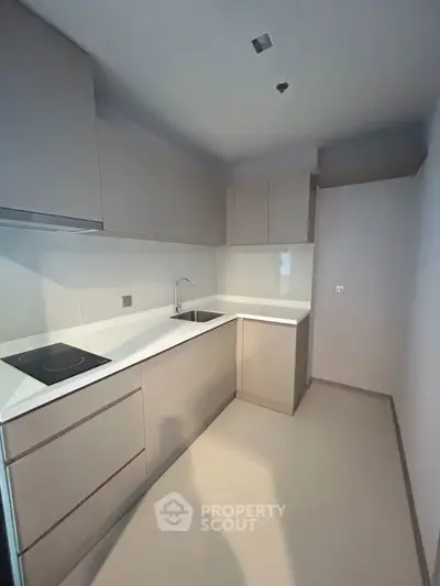 Modern kitchen with sleek cabinetry and electric cooktop in minimalist design.