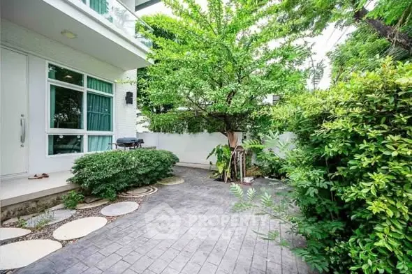 Charming garden area with lush greenery and modern patio in a serene residential setting.