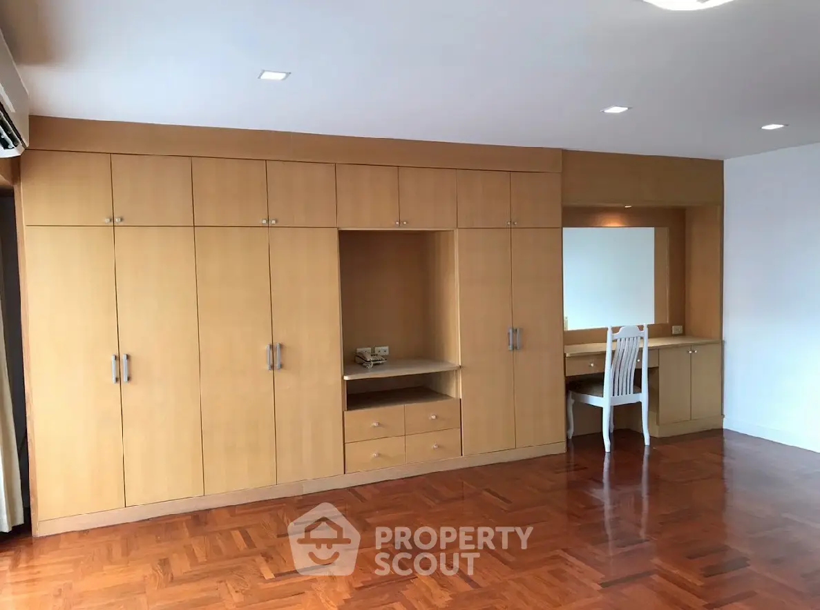 Spacious bedroom with built-in wooden wardrobe and elegant parquet flooring