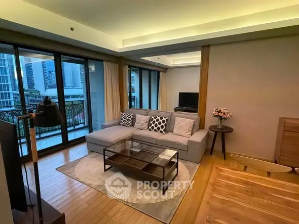 Spacious living room with modern decor and large windows opening to a balcony with city views.