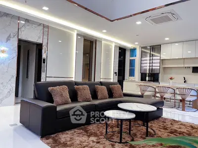 Luxurious modern living room with sleek black sofa and elegant kitchen area.