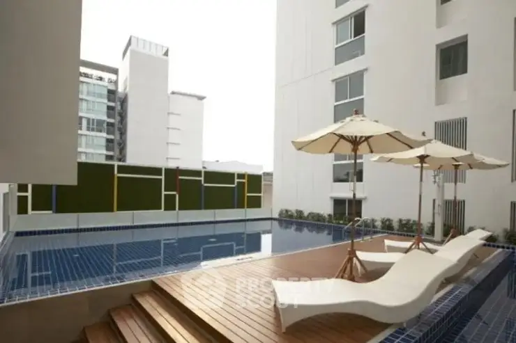 Luxurious modern apartment pool area with stylish loungers and umbrellas, perfect for relaxation.