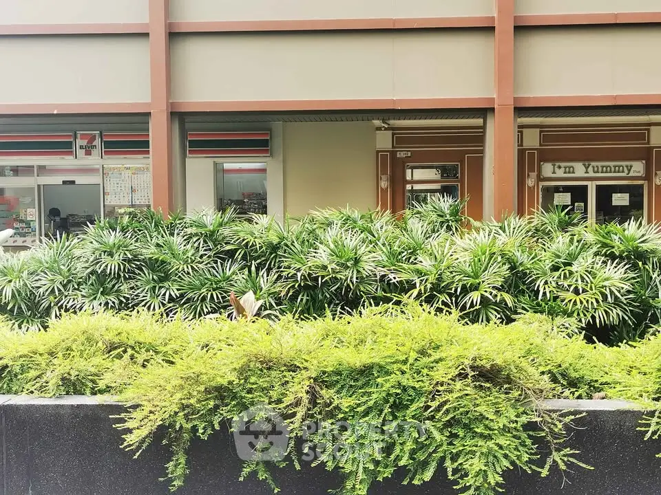 Modern building exterior with lush greenery and storefronts