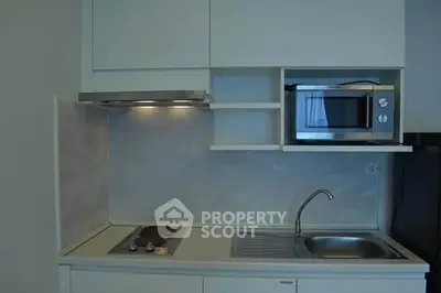 Modern compact kitchen with sleek cabinetry and built-in microwave