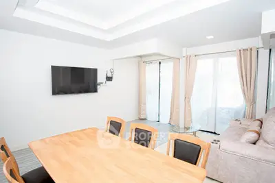 Spacious modern living room with natural light, sleek furniture, and wall-mounted TV, perfect for relaxation.