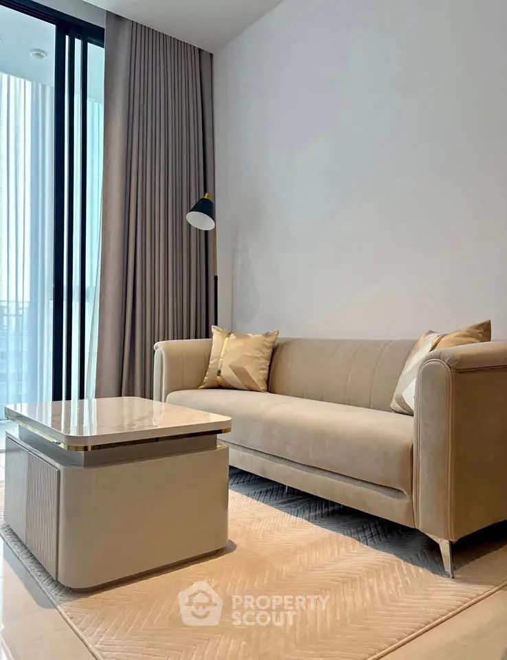 Modern living room with elegant beige sofa and sleek coffee table, featuring floor-to-ceiling windows and stylish decor.