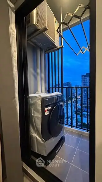Modern apartment balcony with washing machine and city view at dusk